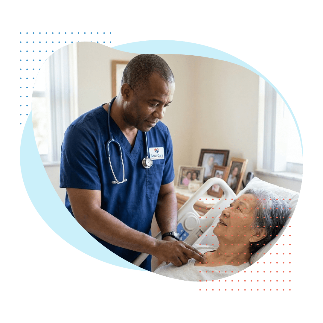 A middle-aged Haitian male private duty nurse with a stethoscope and Best Care logo is carefully monitoring the pulse of an elderly Chinese woman resting comfortably in a neat, well-lit private home bedroom in Miami Springs.